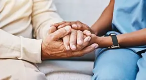 Close-up of elderly person and medical worker holding hands