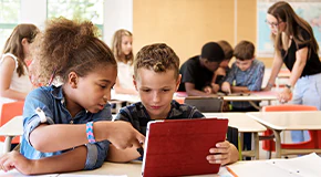 Children in classroom scrolling through a tablet