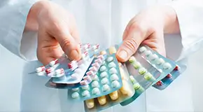Doctor holding out several packs of a variety of pills