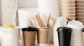 Assortment of stacked disposable coffee cups, coffee lids, oyster pails, and utensils