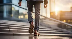 Low angle shot of a businessman walking up stairs to a glass building during golden hour
