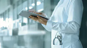 Healthcare worker standing outside and using a tablet