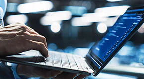 Person holding the bottom of a laptop in one hand and typing with the other hand