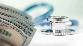 Six 100-dollar bills next to a stethoscope