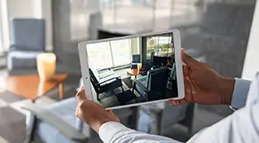 Hands holding computer tablet in room with photo on screen