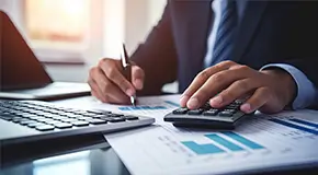 Business person working on a calculator and computer